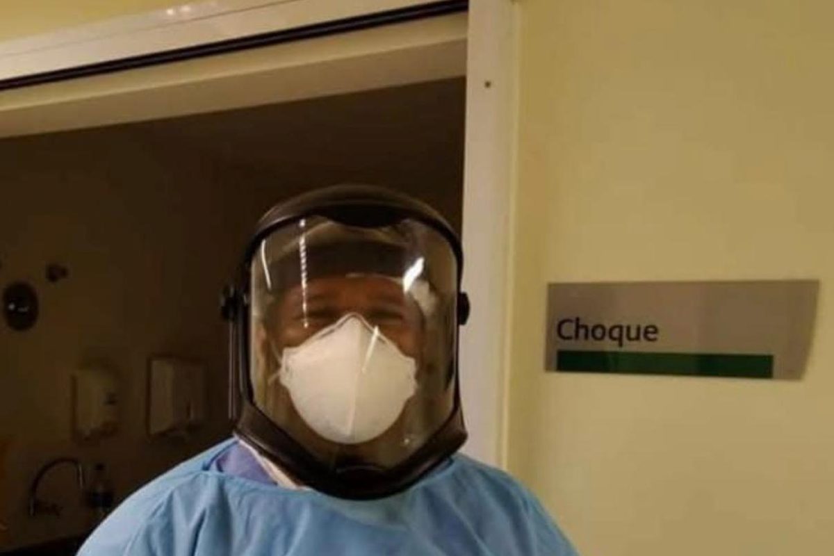 Profissional de saúde com avental, máscara e protetor facial em área hospitalar