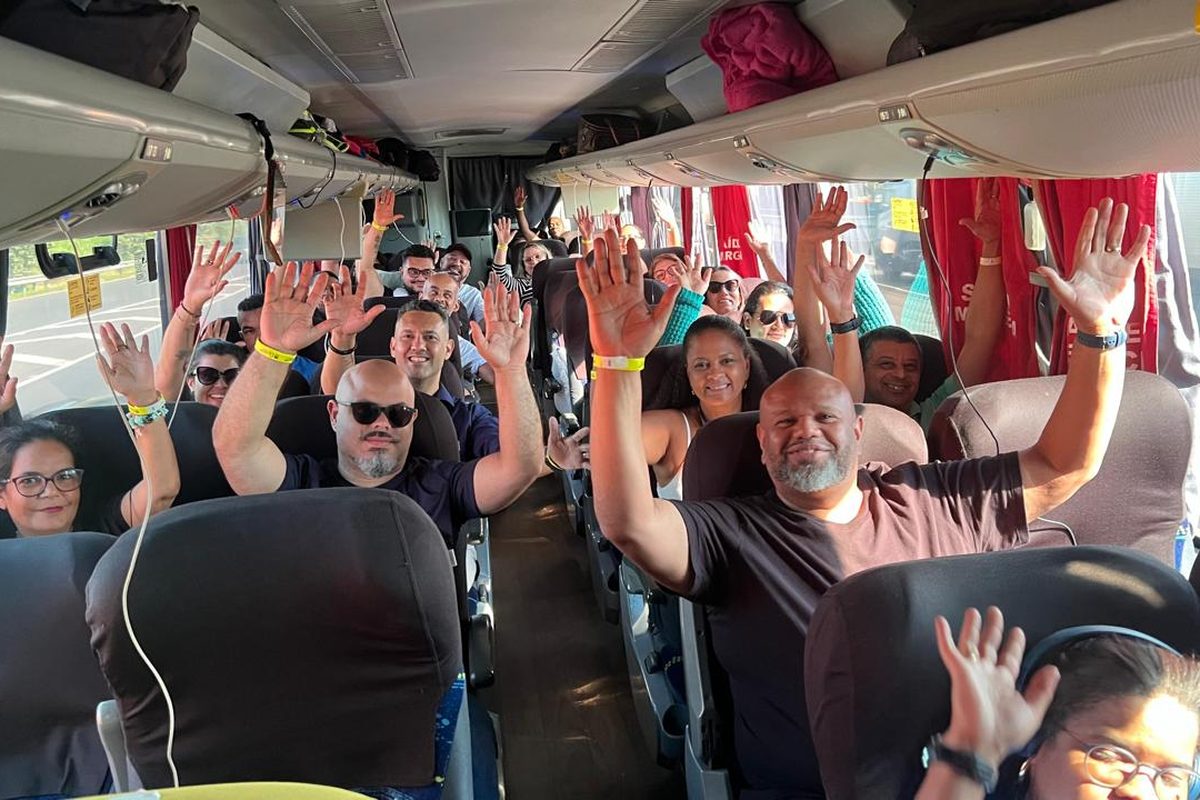 Profissionais de saúde numa caravana de ônibus, com as mãos levantadas