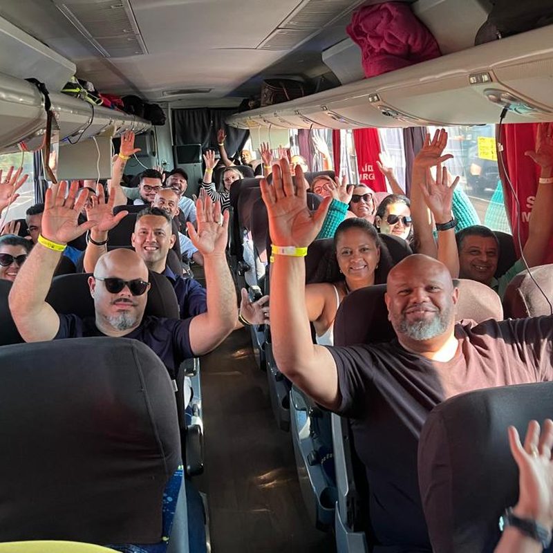 Caravana de profissionais de saúde em um ônibus, com as mãos levantadas